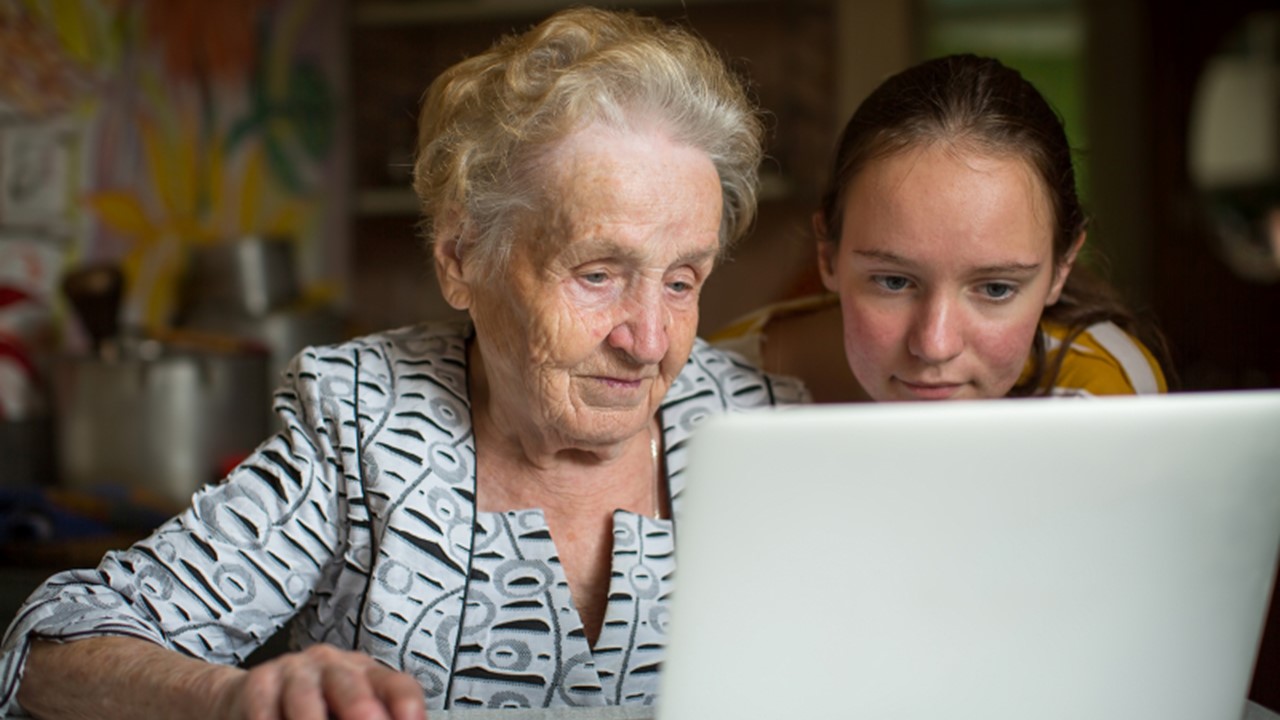 Bild på äldre och yngre person vid dator