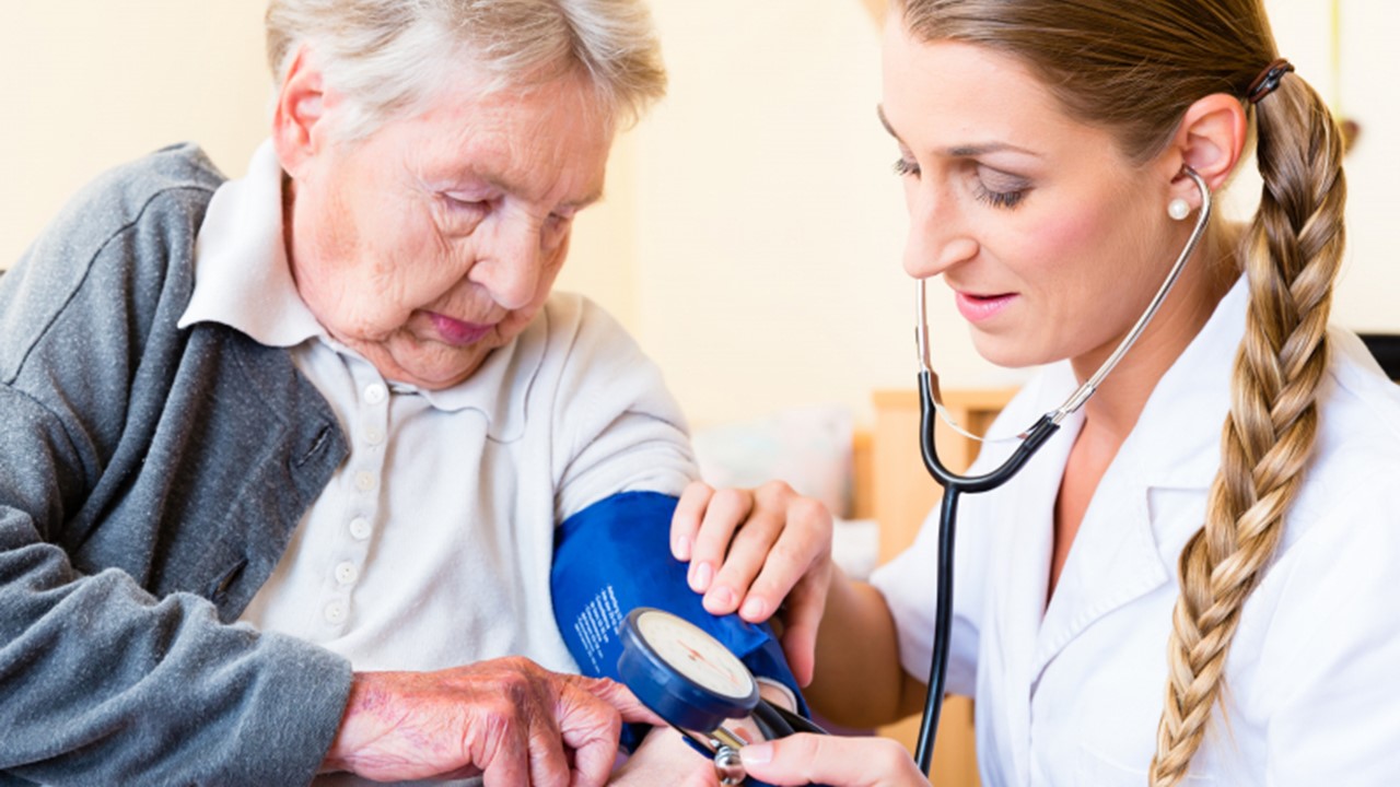 Vårdpersonal som tar blodtrycket på äldre person